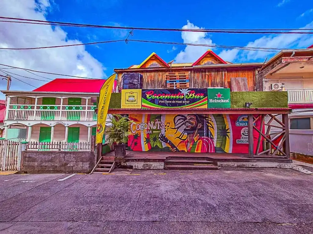 açade colorée du Coconuts Bar à Terre-de-Haut, Les Saintes, avec fresque murale et enseignes caribéennes