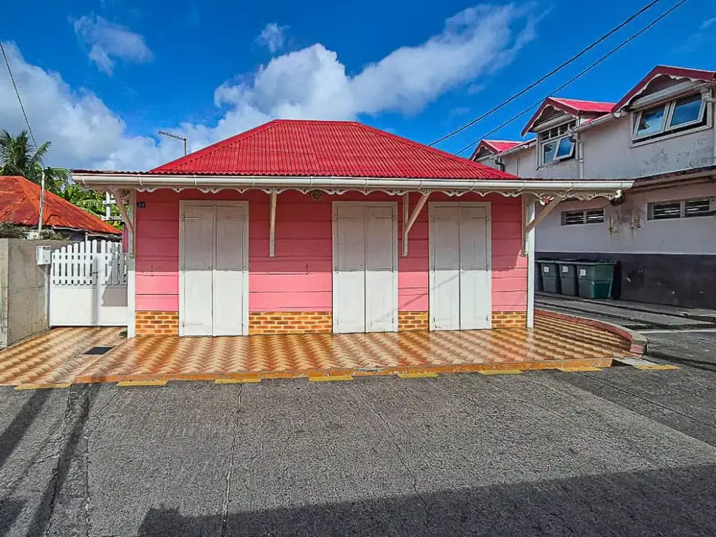 Maison colorée à Terre-de-Haut, Les Saintes, avec façade rose, toit rouge et terrasse carrelée