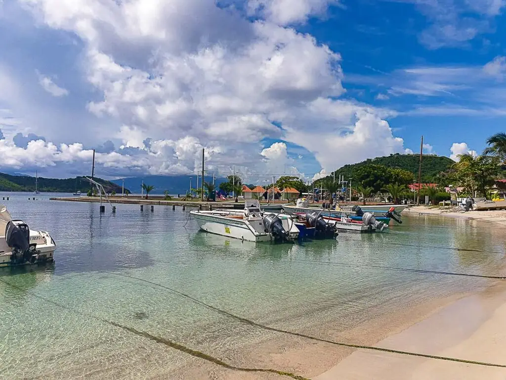 Plage de Terre-de-Haut, Les Saintes, avec petits bateaux amarrés dans une eau turquoise et collines verdoyantes